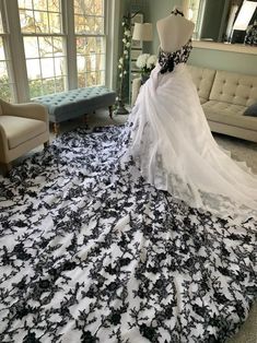 a wedding dress on display in a room with couches and windows, all covered in black and white fabric