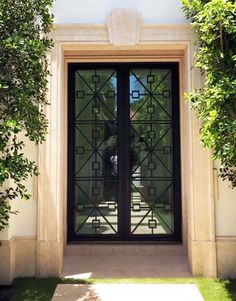 an entrance to a building with glass doors and plants growing on the side of it