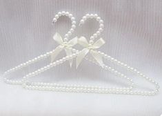 a white headband with pearls and bows on it's side is shown in the shape of a heart