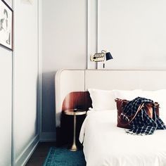 a bed with a white headboard and pillows on top of it next to a night stand