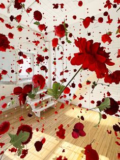 red flowers floating in the air over a wooden floor with white walls and wood floors