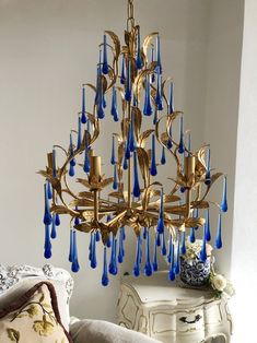 a gold chandelier with blue glass drops hanging from it's centerpiece