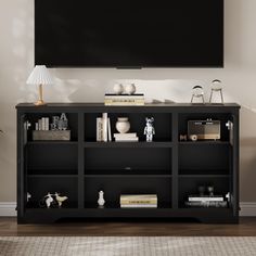 a black entertainment center with bookshelves and lamps on the top shelf, in front of a flat screen tv