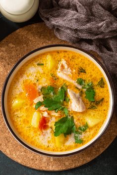 a bowl of chicken and pineapple soup with a glass of milk next to it