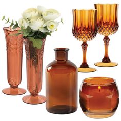 several vases and glasses are arranged on a white background, including one with flowers in it