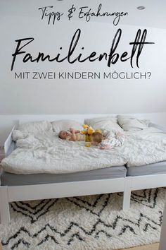 a baby laying on top of a bed under a wall sticker that reads, familienebett