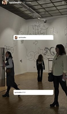 two women standing in an art gallery looking at artwork on the walls and talking to each other