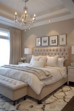 a bedroom with a large bed, chandelier and two pictures on the wall