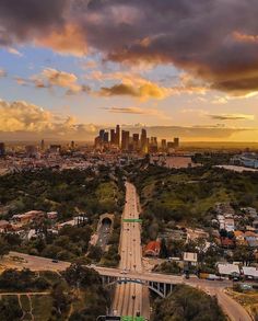 an aerial view of a highway and the city in the distance with clouds above it