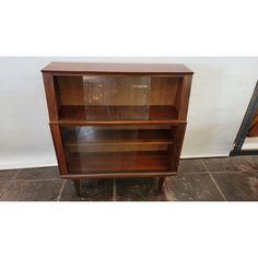 a wooden bookcase sitting on top of a tiled floor