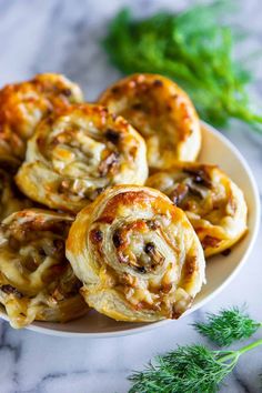 some very tasty looking pastries on a white plate with green sprigs