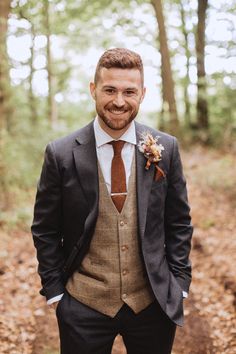 a man wearing a suit and tie standing in the woods