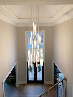 a chandelier hanging from the ceiling in an empty room with stairs leading up to it