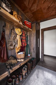 an entryway with wooden walls and shelves filled with hats, boots and other items