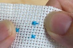 someone is stitching something on the fabric with their thumbnails and finger tips