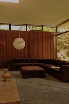 a living room filled with lots of furniture next to a wall covered in wood paneling