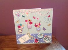 a greeting card with flowers and butterflies on it, sitting on a table next to a pair of scissors