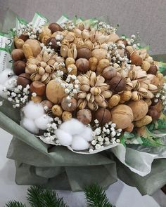 a bouquet of nuts and flowers on top of a green cloth with pine cones in the background