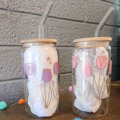 two glass jars with straws in them sitting next to each other on a table