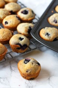 blueberry muffins cooling on a wire rack next to a tray of muffins