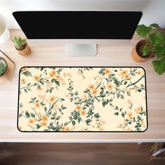 a computer desk with a flowery pattern on the mouse pad and keyboard next to it