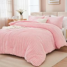 a bed with pink comforter and pillows in a room