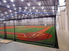 an indoor baseball field with lights on the ceiling and grass in the outfield area