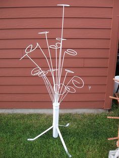 a white metal tree with lots of different items on it's branches in front of a red building