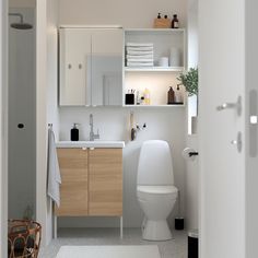 a white toilet sitting next to a bathroom sink under a mirror on top of a wooden cabinet