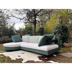 a green and white couch sitting on top of a grass covered field next to a tree