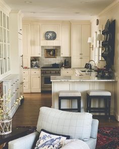 a living room filled with furniture and a kitchen in the back drop off wall behind it