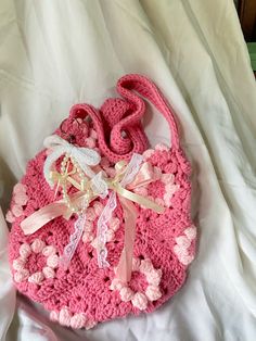 a pink crocheted purse sitting on top of a bed