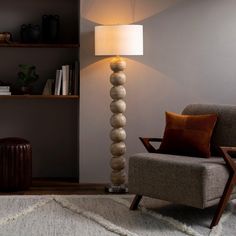 a lamp sitting on top of a wooden floor next to a chair in a living room