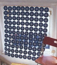 an empty chair sitting in front of a window with circles on the wall behind it