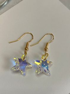 These handmade, beautiful crystal starfish earrings are made from Clear AB Crystal Starfish. They reflect the colors around them and glisten in the sun. Gorgeous! The starfish are 14mm wide and are dangling from gold plated French hooks. Perfect for beach vacations or anytime you are feeling beachy. These earrings come adorably packaged in an organza gift bag, with the “starfish story” card included. These make great appreciation gifts for teachers, mentors, friends, or anyone who is making a difference. Gold Star-shaped Crystal Earrings For Pierced Ears, Starfish-shaped Earrings With Star Charm For Gift, Starfish Earrings With Star Charm As Gift, Starfish Ear Wire Jewelry As Gift, Celestial Star-shaped Crystal Earrings For Gift, Celestial Star-shaped Crystal Earrings Gift, Star-shaped Crystal Earrings For Gifts, Star Charm Earrings For Jewelry Making, Celestial Star-shaped Crystal Earrings