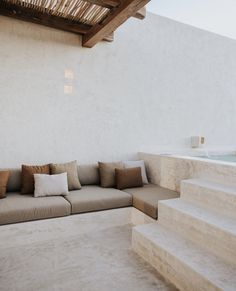 a couch sitting on top of a white floor next to a wooden ceiling and stairs