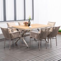 a wooden table with four chairs around it on a tiled floor next to a window