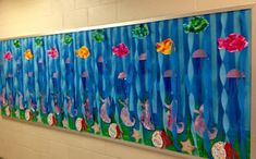 an art project is displayed on the wall in front of a school hallway with flowers and fish painted on it