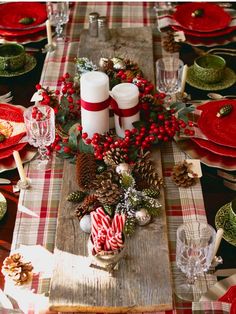 a christmas table setting with candles, candy canes and pine cones