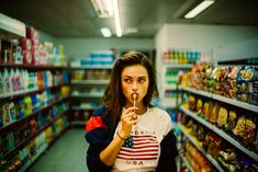 a woman is standing in a grocery store holding a toothbrush up to her mouth