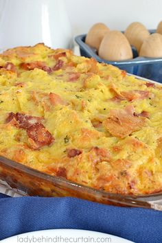 a casserole dish with ham and eggs in the background on a blue towel