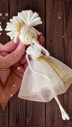 a hand holding a small white doll in it's left hand, next to a string net