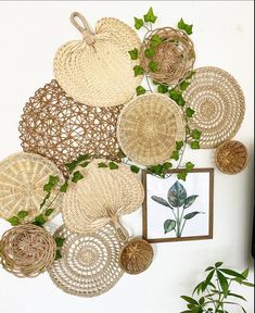 wicker baskets are arranged on the wall above a potted plant and framed photograph