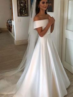 a woman in a white wedding dress standing next to a doorway and wearing a veil