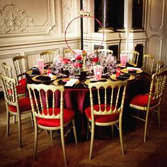 a dining room table set with red and gold chairs