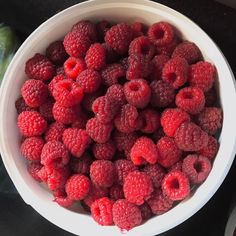 a bowl filled with raspberries on top of a table