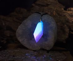 a purple and blue pendant sitting on top of a rock