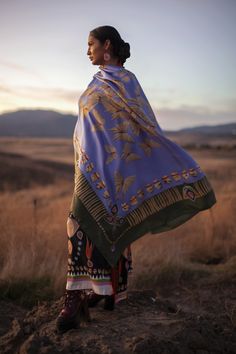 a woman standing on top of a hill covered in a blanket