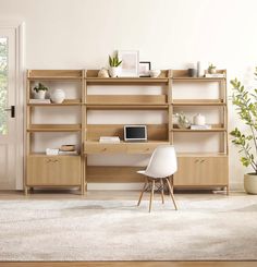 a white chair sitting in front of a wooden shelf filled with books and plants on top of it