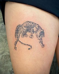 a woman's thigh with a tattoo of a tiger on the side, and an outline of a cat